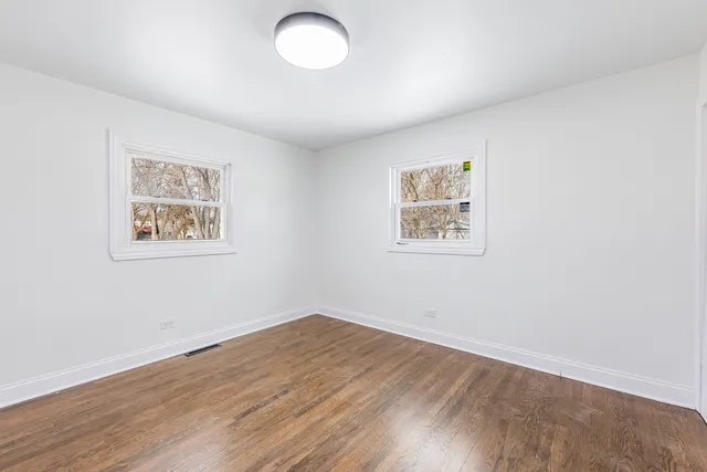 an empty room with wooden floor and window