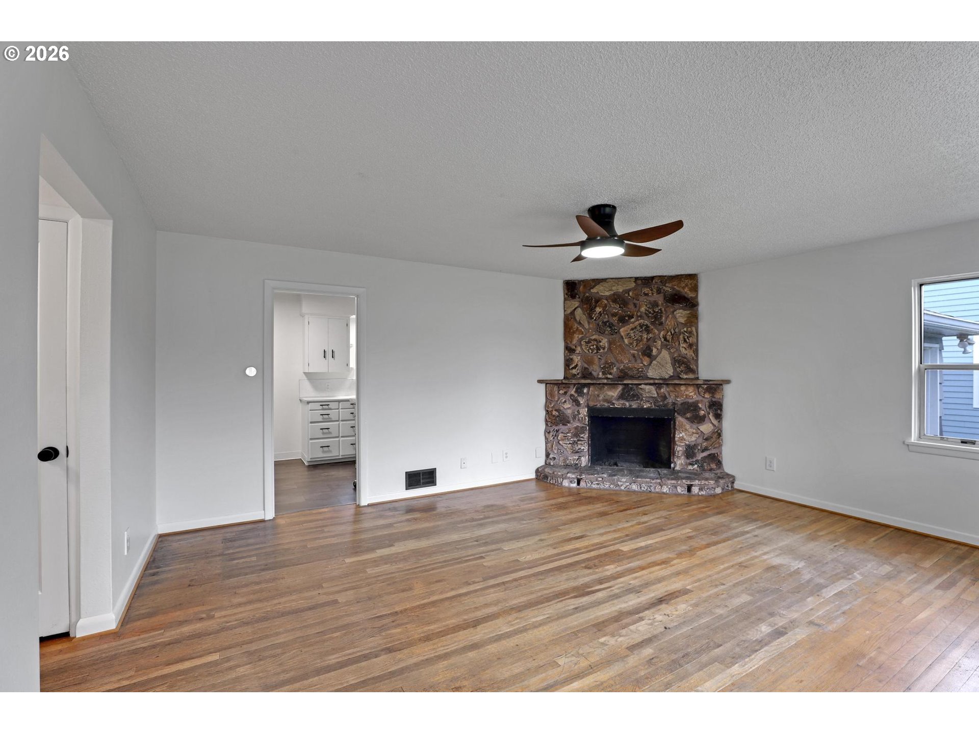 8915 Southeast Market Street Portland, OR 97216 - Photo 3 of 26 a view of an empty room with wooden floor fireplace and a window