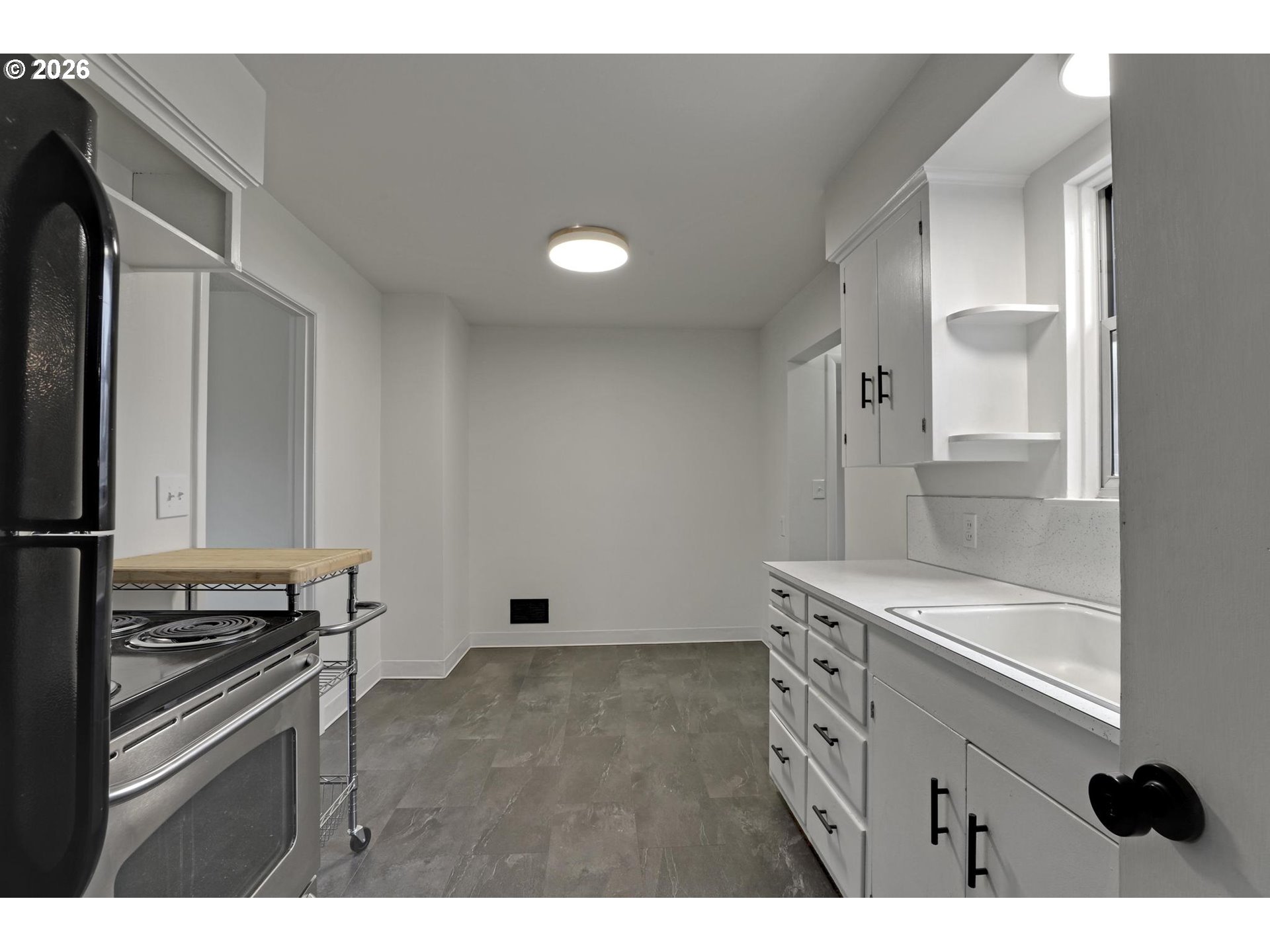 8915 Southeast Market Street Portland, OR 97216 - Photo 9 of 26 a kitchen with kitchen island white cabinets and stainless steel appliances