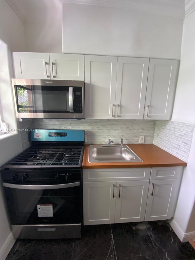 1227 Euclid Avenue, Unit 6 Miami Beach, FL 33139 - Photo 13 of 24 a kitchen with granite countertop white cabinets and stainless steel appliances