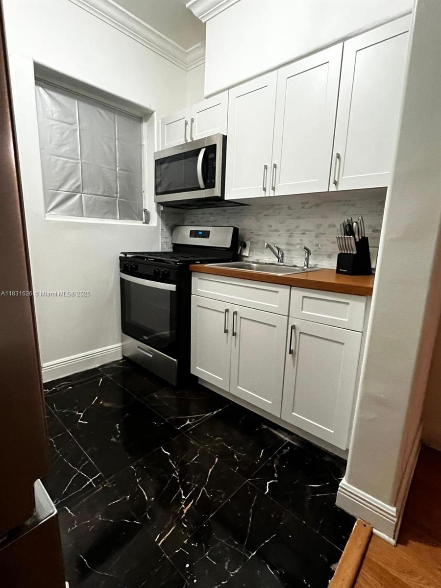 1227 Euclid Avenue, Unit 6 Miami Beach, FL 33139 - Photo 15 of 24 a kitchen with stainless steel appliances a stove a sink and a microwave