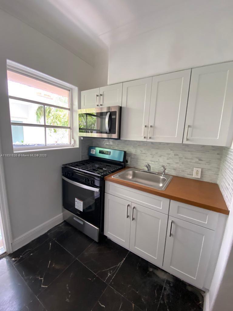 1227 Euclid Avenue, Unit 6 Miami Beach, FL 33139 - Photo 18 of 24 a kitchen with granite countertop white cabinets and white appliances