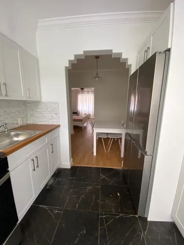 a kitchen with granite countertop a refrigerator and a stove top oven