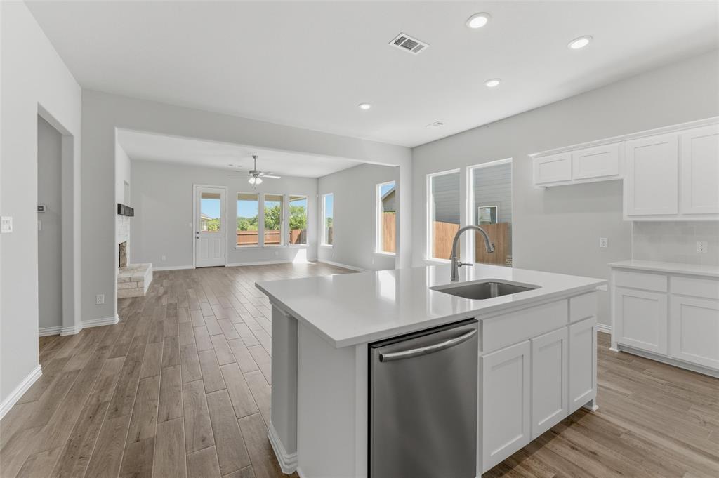 1225 Sabine River Lane Springtown, TX 76082 - Photo 25 of 25 Kitchen featuring stainless steel dishwasher, light wood-style flooring, an island with sink, white cabinetry, and open floor plan