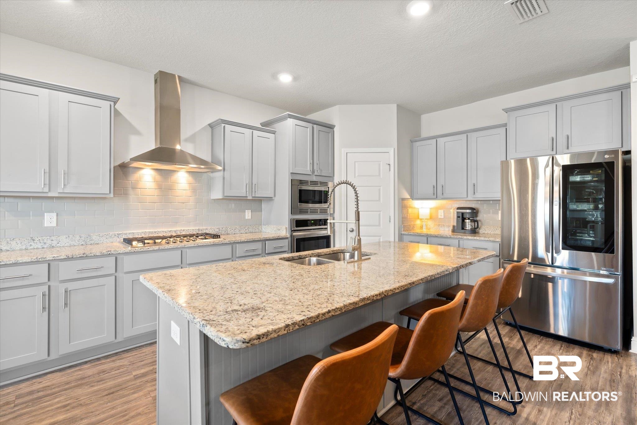 12899 Sanderling Loop Daphne, AL 36527 - Photo 9 of 28 Kitchen featuring wall chimney exhaust hood, stainless steel appliances, light wood-type flooring, and an island with sink