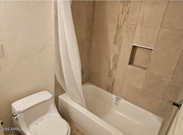 a white toilet sitting next to a bath tub