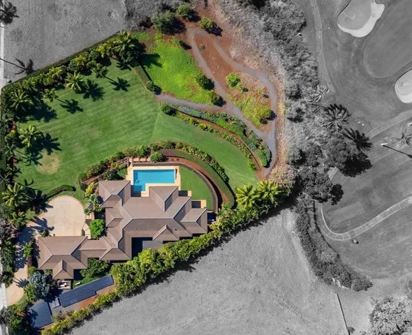 an aerial view of a house with a yard and greenery