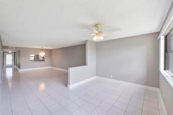 a view of an empty room with window and chandelier fan