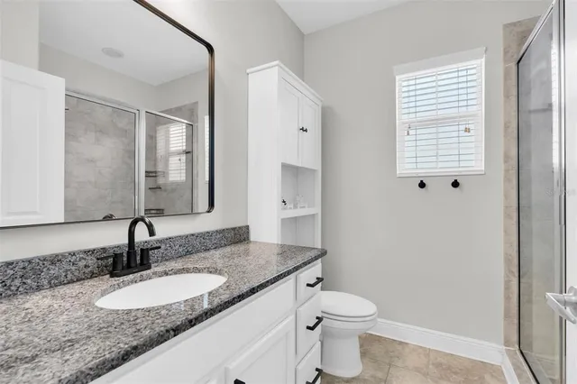 a bathroom with a granite countertop sink toilet and mirror