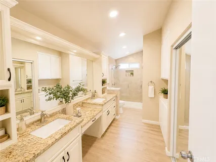 a large bathroom with a granite countertop double vanity sink a bathtub and shower
