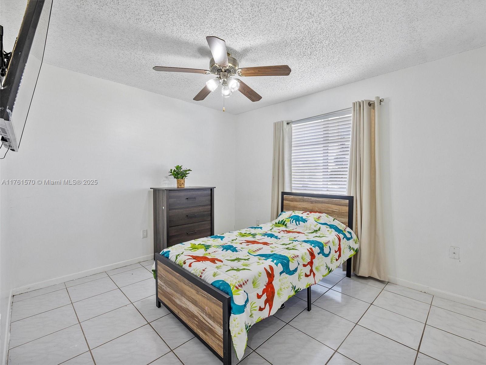 12744 Southwest 261st Terrace Homestead, FL 33032 - Photo 13 of 26 a bedroom with a bed and a chandelier