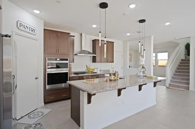 a kitchen with stainless steel appliances granite countertop a sink a stove and a refrigerator