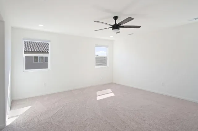 an empty room with windows and fan