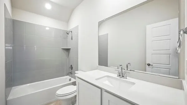 a bathroom with a granite countertop bathtub shower sink vanity mirror and toilet