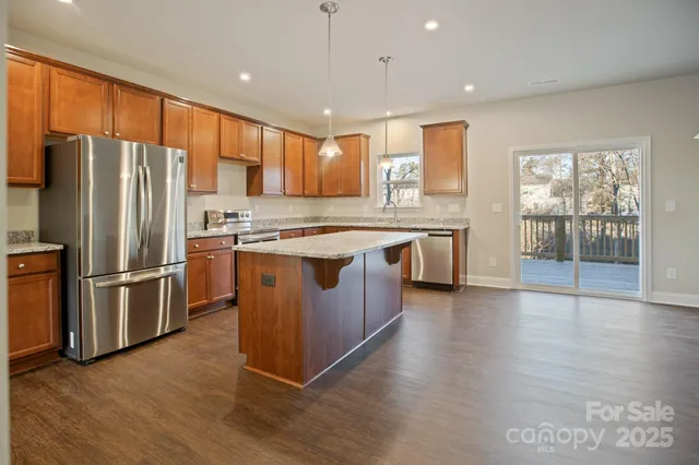 a kitchen with stainless steel appliances granite countertop a refrigerator a sink dishwasher a stove with wooden floors and cabinets