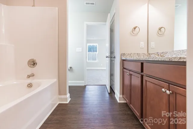 a bathroom with a granite countertop tub shower and mirror