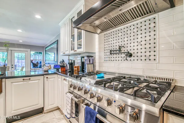 a dining room with stainless steel appliances kitchen island granite countertop a table chairs and a rug