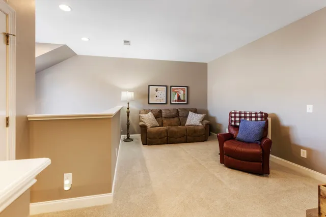 a bedroom with a bed a computer on the desk and a dresser next to a window