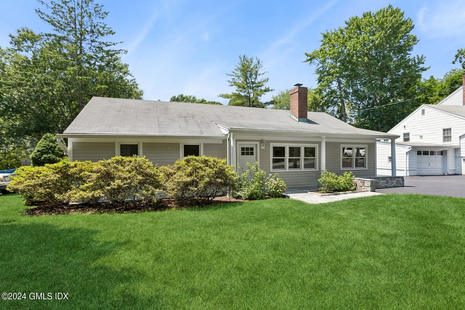 a front view of a house with a garden and trees