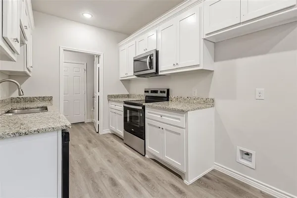 a kitchen with granite countertop white cabinets and white appliances