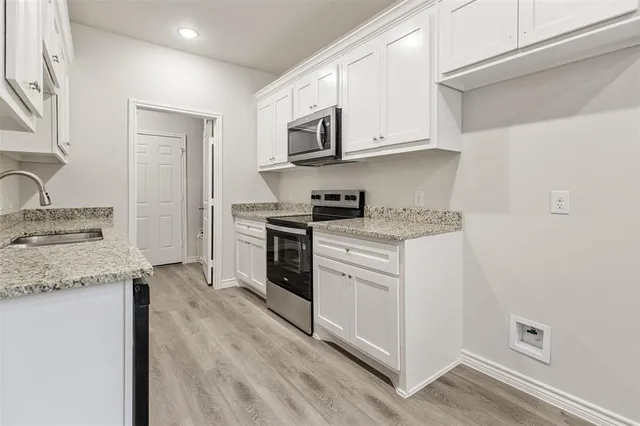 a kitchen with granite countertop white cabinets and white appliances