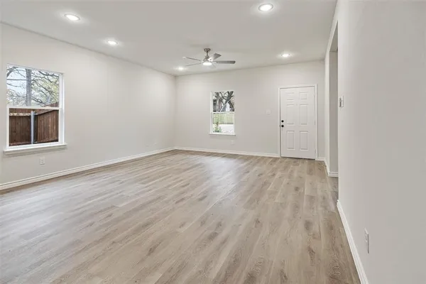 an empty room with wooden floor and windows