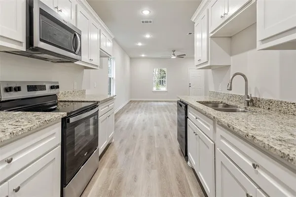 a kitchen with stainless steel appliances granite countertop a sink a stove top oven and wooden floor