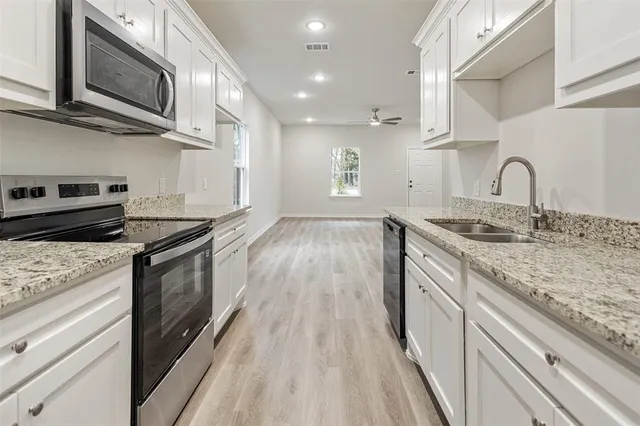 a kitchen with stainless steel appliances granite countertop a sink a stove top oven and wooden floor