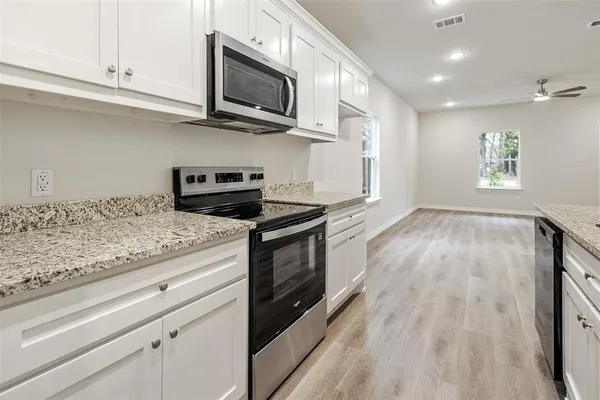 a kitchen with granite countertop wooden cabinets stainless steel appliances and a window