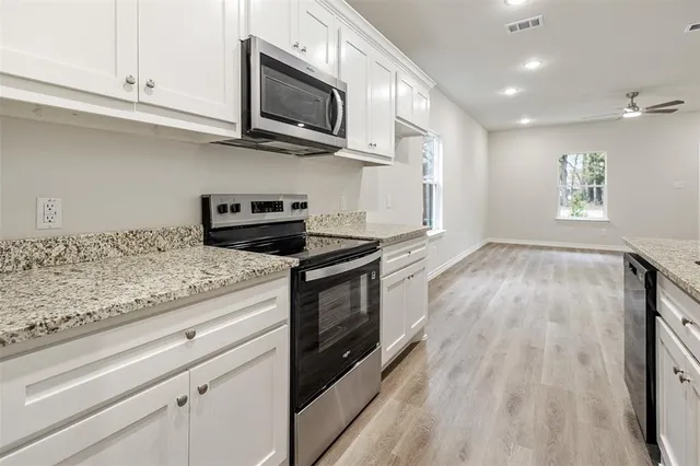 a kitchen with granite countertop wooden cabinets stainless steel appliances and a window