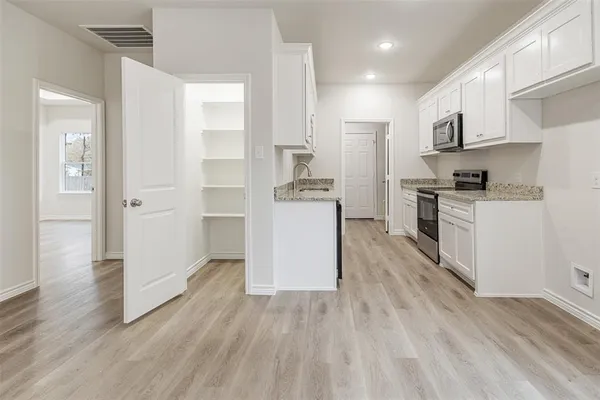 a kitchen with stainless steel appliances granite countertop a stove top oven a refrigerator a sink and dishwasher with wooden floor