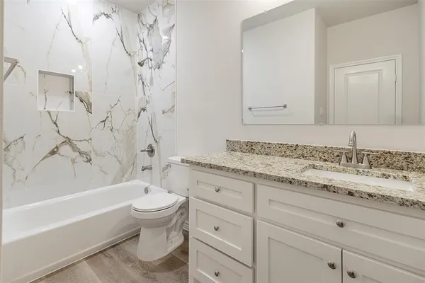 a bathroom with a granite countertop sink a toilet and bathtub