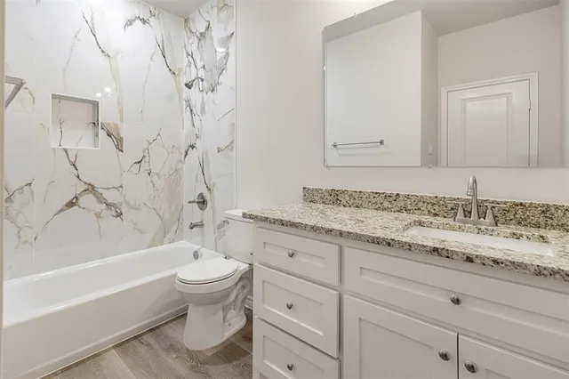 a bathroom with a granite countertop sink a toilet and bathtub
