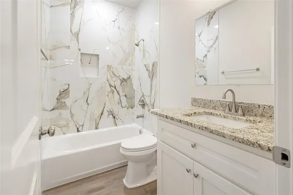 a bathroom with a granite countertop sink toilet and shower