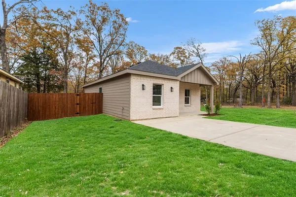 a view of a yard in front of a house with large trees