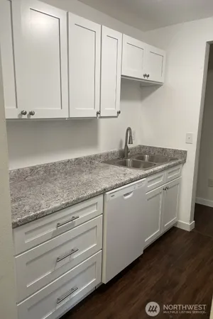 a kitchen with granite countertop white cabinets and a sink