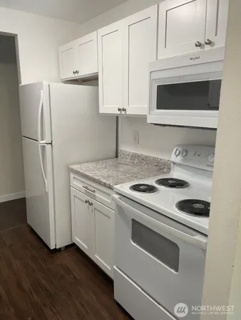 a kitchen with granite countertop white cabinets and white appliances