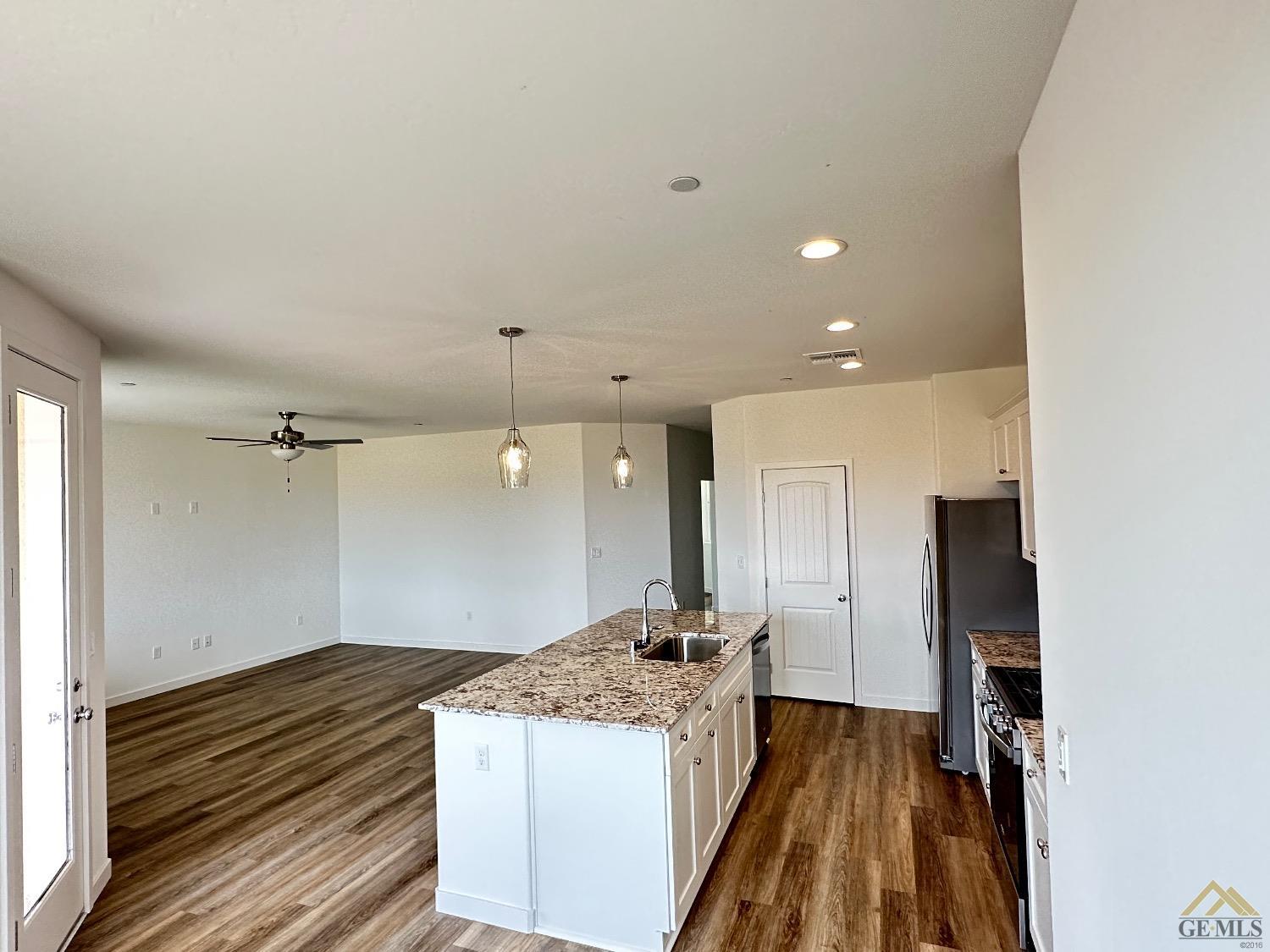 Undisclosed Address Bakersfield, CA 93311 - Photo 3 of 13 a large kitchen with a refrigerator a sink dishwasher a stove and a dining table with wooden floor