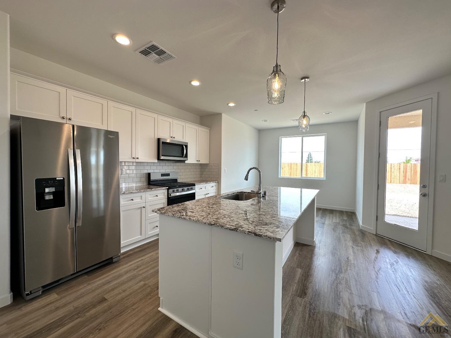 Undisclosed Address Bakersfield, CA 93311 - Photo 5 of 13 a kitchen with stainless steel appliances granite countertop a refrigerator a sink dishwasher a stove and white countertops with wooden floor