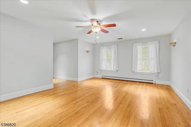 a view of an empty room with window and wooden floor