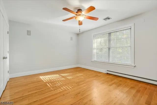 a view of an empty room with window and a chandelier fan