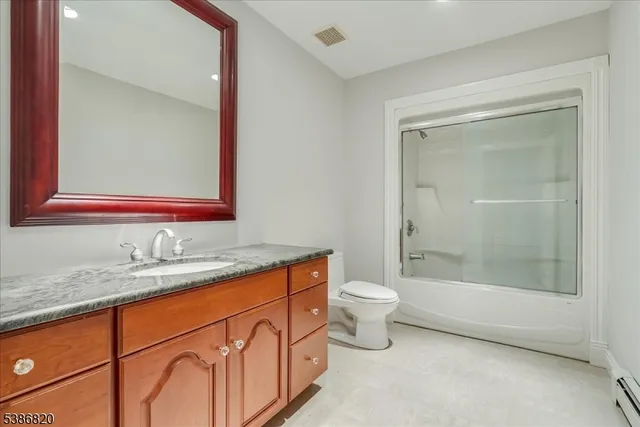 a bathroom with a granite countertop sink mirror vanity and toilet