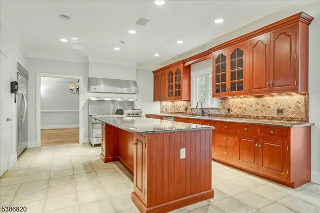 a large kitchen with stainless steel appliances granite countertop a large counter top and a refrigerator