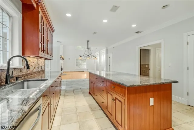 a large kitchen with kitchen island granite countertop a sink and white cabinets