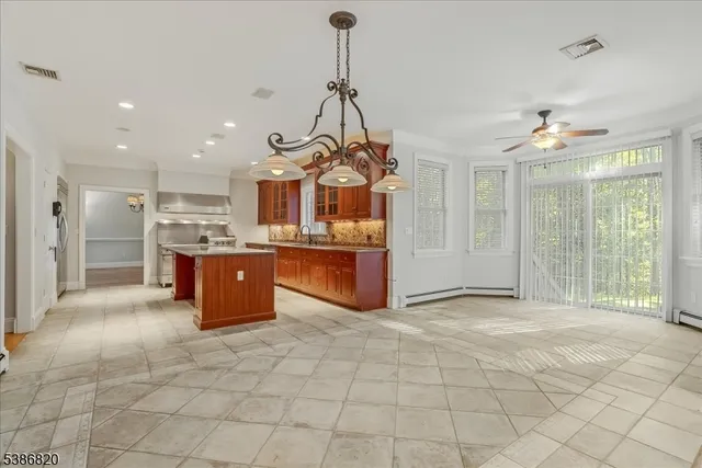 a view of a kitchen with kitchen island granite countertop a stove top oven a sink a counter top space and cabinets