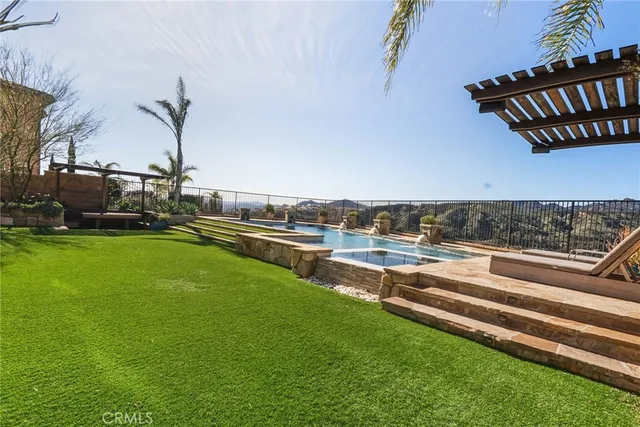 a view of a swimming pool with lawn chairs and a big yard