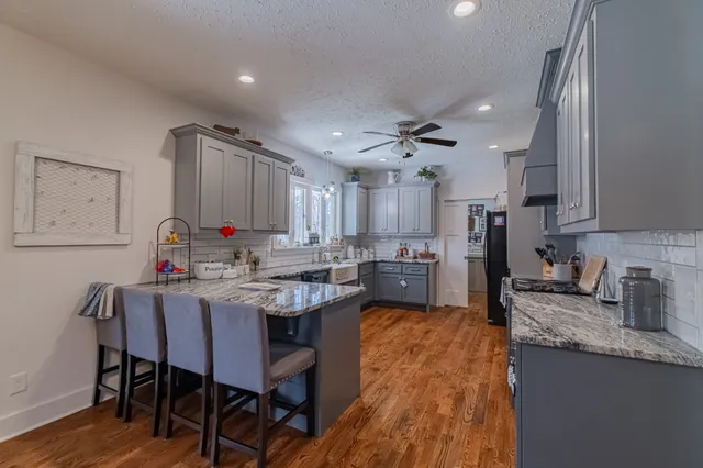 a kitchen with cabinets a sink dishwasher a dining table and chairs with wooden floor