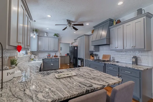 a kitchen with stainless steel appliances kitchen island granite countertop a sink stove and cabinets