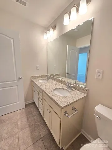 a bathroom with a granite countertop sink a toilet a mirror and shower