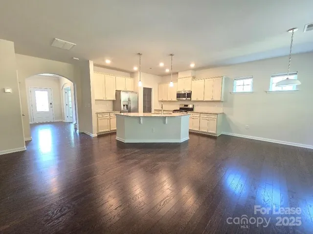 a living room with stainless steel appliances kitchen island granite countertop wooden floors and view living room